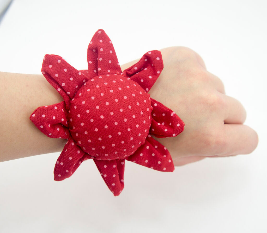 Close-up of red wrist pin cushion showing pin placement