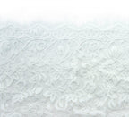 Fine pattern wide corded lace in white displayed on a flat surface.