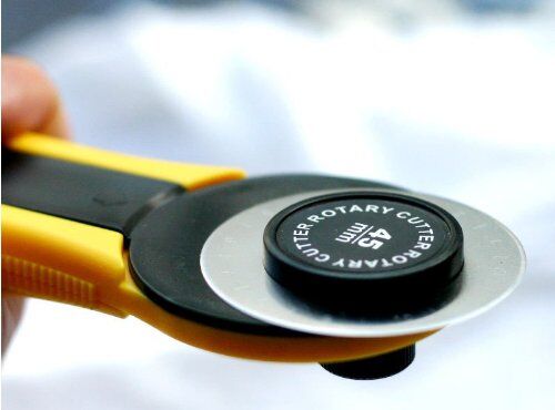 A rotary cutter in use, demonstrating the blade cutting fabric.