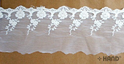Close-up of vintage cream tulle lace with intricate embroidery.