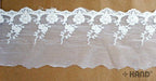 Close-up of vintage cream tulle lace with intricate embroidery.
